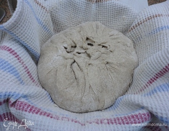 У кого есть расстоечная корзина, перекладывает в нее. В противном случае, как у меня, берем любую миску, выстилаем ее полотенцем и хорошо посыпаем ржаной мукой. Осторожно перекладываем хлеб швом вверх. Прикрываем пленкой. Я же просто подвернула краями полотенца. Оставляем при комнатной температуре на расстойку на 1,5–2 часа.