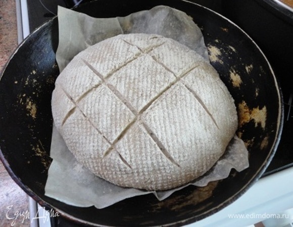 Выкладываю осторожно хлеб швом вниз, быстро делаю надрезы и ставлю в духовку, снизив температуру до 200°C и поставив на дно чашку с кипящей водой. Выпекаем хлеб 50 минут. Через 10 минут после начала выпечки воду убираем.