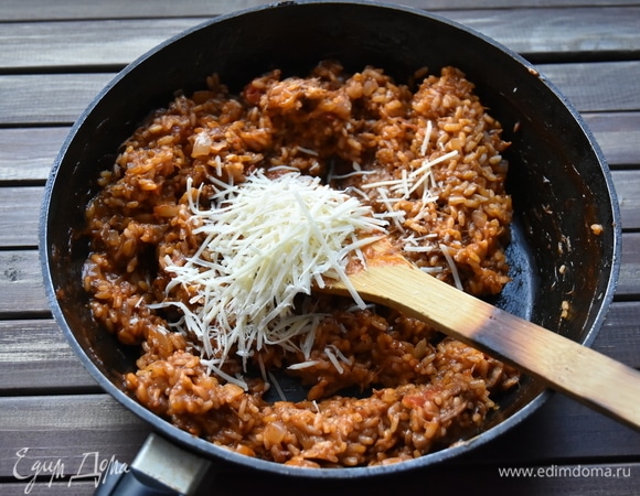 Когда рис будет почти готов, добавить тертый пармезан. Перемешать ризотто.