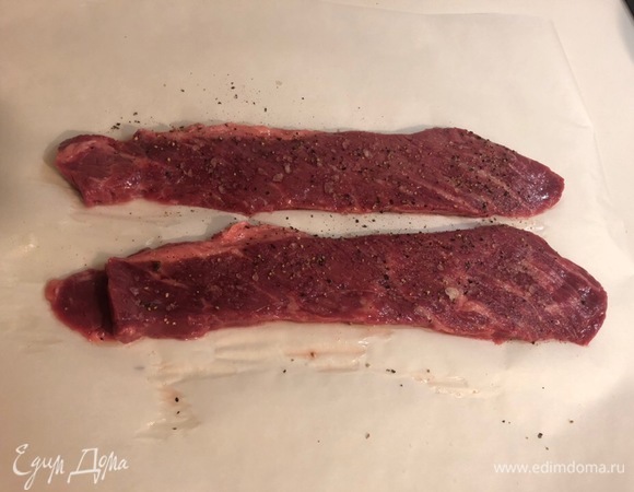 Мясо должно быть комнатной температуры, поэтому если оно лежало в холодильнике, его нужно достать за полчаса-час до готовки. Кладем мясо на бумагу для выпечки, солим крупной морской солью и перчим по вкусу.