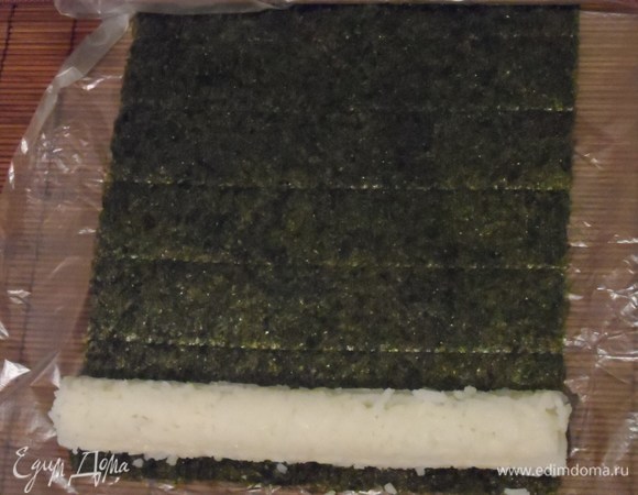 Выложить на рис сыр и огурец. С помощью циновки начать заворачивать ролл.