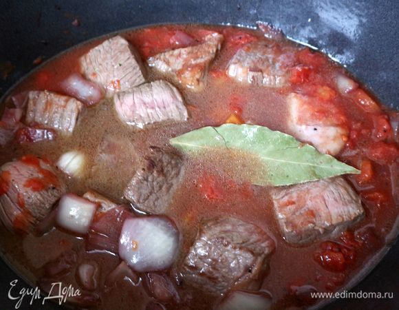 Поместить мясо в жаровню, добавить консервированные в собственном соку томаты, бульон. Мясо должно быть не до конца покрыто жидкостью. Кусочки мяса должны быть видны на поверхности жидкости. Добавить лавровый лист.