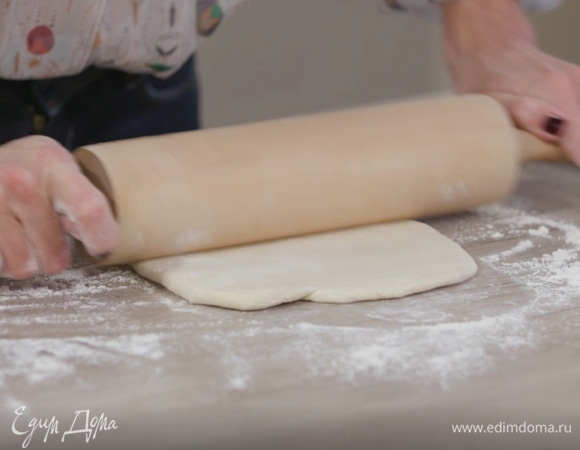 Присыпать рабочую поверхность оставшейся мукой и раскатать половину подошедшего теста в тонкий пласт (оставшееся тесто можно заморозить).