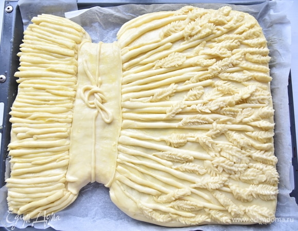 Украсить пирог по желанию. Дать время пирогу на расстойку. Смазать верх пирога яичным желтком и выпекать в духовке, разогретой до 180°C, минут 35–40.