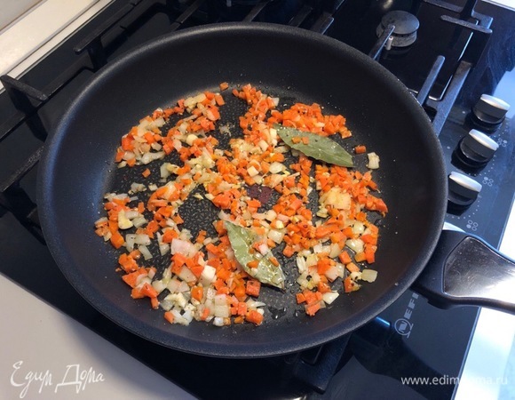 Разогрейте на сковороде растительное масло и обжарьте на нем нарезанный лук (примерно 2–3 минуты). Добавьте к луку морковь, чеснок и лавровый лист, перемешайте и обжаривайте еще 2 минуты.