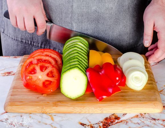 Нарежьте кружочком помидоры, кабачок и репчатый лук. Перцы нарежьте треугольником.