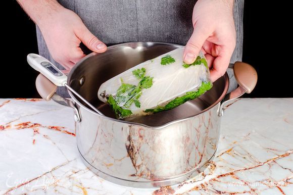 Через полчаса оберните стейк пищевой пленкой и положите в кастрюлю с водой при температуре 50°C. Держите рыбу в воде в течение 1 часа.