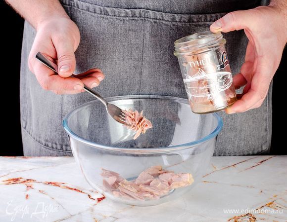 Откройте консервированного тунца ТМ «Капитан Вкусов», слейте жидкость, слегка раздавите вилкой в глубоком салатнике.