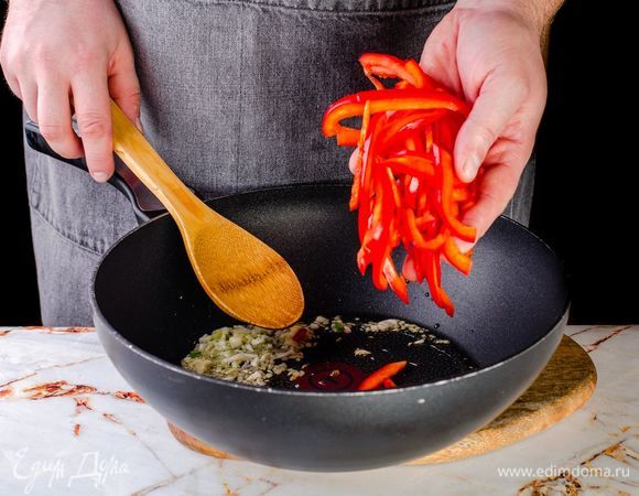 Обжарьте чеснок и имбирь на оливковом масле в течение 1 минуты. Добавьте в сковороду перец и готовьте еще 2–3 минуты.