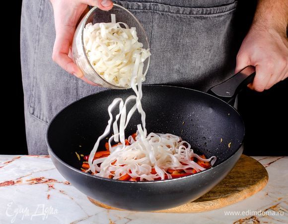 Отварите рисовую лапшу согласно инструкции на упаковке и отправьте в сковороду.<br />
 
