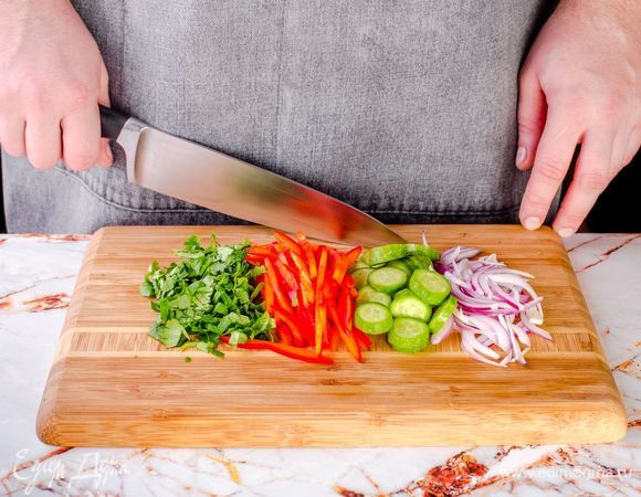 Нарежьте красный лук полукольцами. Перец очистите от семян, нарежьте соломкой. Измельчите кинзу, огурцы нарежьте кружочками.