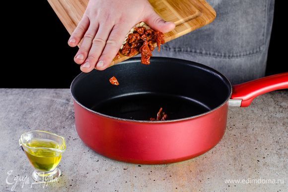 В глубокой сковороде разогрейте немного оливкового масла, поджарьте измельченный чеснок. Добавьте нарезанные вяленые помидоры. Посолите и поперчите.