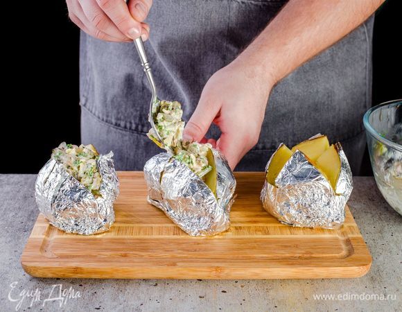 Пока картофель горячий, разрежьте каждую картофелину и наполните начинкой, украсьте сверху зеленью.