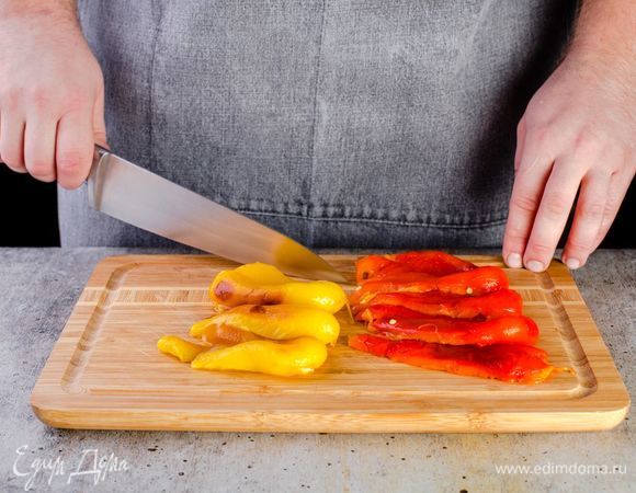 Когда перец приготовится, положите его в миску, накройте пищевой пленкой, чтобы он немного размяк. Очистите от кожуры нарежьте крупными полосками.