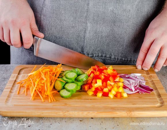 Нарежьте ингредиенты: лук и морковь — соломкой, перцы — кубиком, огурцы — кружочками.