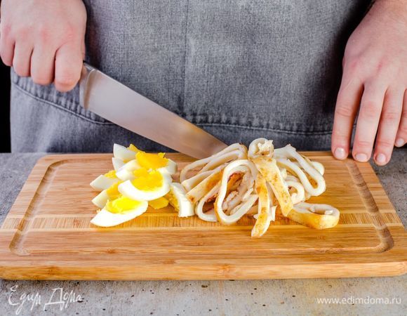 Обжареные кальмары нарежьте кольцами, яйца очистите и нарежьте дольками.