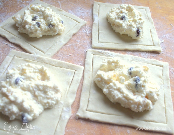 На квадратах теста сделать надрезы и выложить по центру начинку.