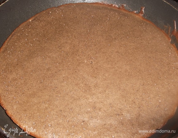 Сковороду застелить пергаментом. Смазать растительным маслом. Половником налить тесто. Поставить в разогретую духовку. Выпекать при 200°C примерно 15 минут. Таким образом испечь 3–4 коржа.