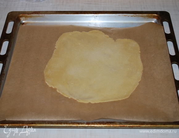 Раскатайте тесто на пергаменте и наколите его вилкой, чтобы оно не пузырилось. Выпекайте в духовке до золотистого цвета примерно 3–4 минуты при температуре 180°C.