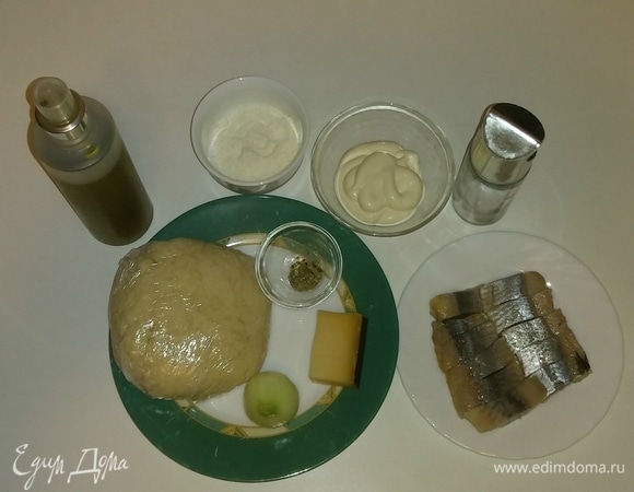 Собираем все необходимые ингредиенты для приготовления пиццы вместе. Я использую кефирное тесто для пиццы, которое было приготовлено заранее и заморожено. Поэтому перед приготовлением пиццы необходимо достать тесто из морозилки заранее и разморозить. Рецепт теста указан здесь: https://www.edimdoma.ru/retsepty/124412-kefirnoe-testo-dlya-pitstsy. На всякий случай коротко напомню ингредиенты для 1 порции теста (для формы диаметром 26 см): блинной муки — 150 г, 1% кефира — 100 мл, щепотка соли и щепотка сахара. Перемешать все вместе.