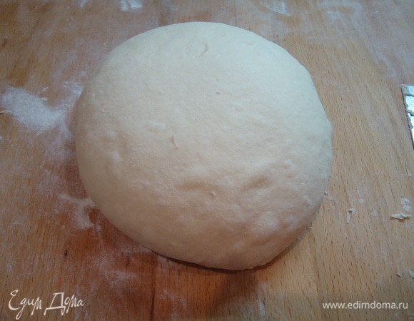 Затем тесто выложить на рабочий стол (стол слегка подпылить мукой). Тесто обмять и свернуть в шар. Для брожения переложить его в смазанную маслом емкость. Оставить в теплом месте на 80 минут. За это время тесто сложить один раз на 40-ой минуте. По окончании тесто выложить на стол, подвернуть в плотный шар.