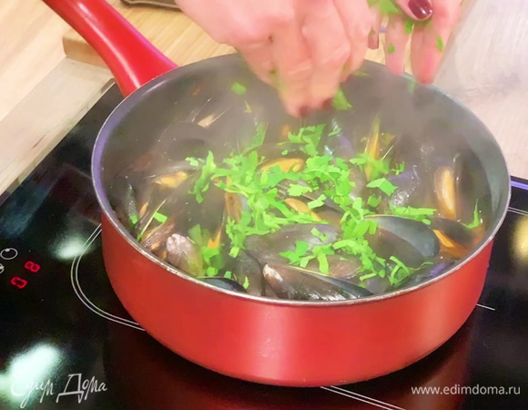 Петрушку мелко порубить, посыпать мидии и снять сотейник с огня.