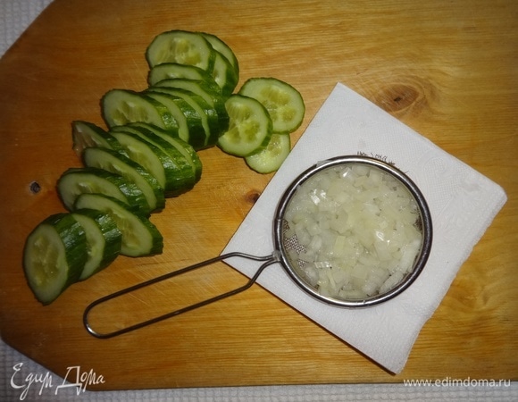 Огурец вымыть, обсушить, нарезать тонкими овалами. Лук очистить, нарезать мелко. Положить лук в сито, обдать сначала кипятком, затем — холодной водой. Дать воде полностью стечь.