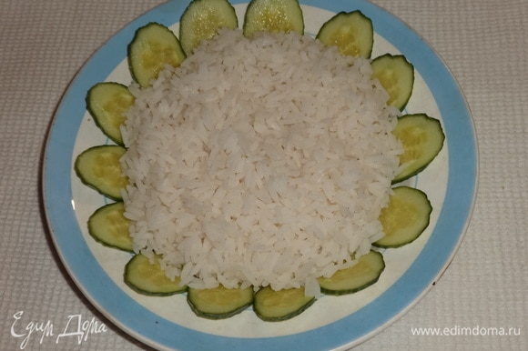 В тарелку выложить вареный рис. По кругу разложить огурцы.