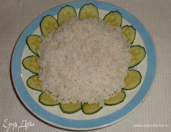 В тарелку выложить вареный рис. По кругу разложить огурцы.