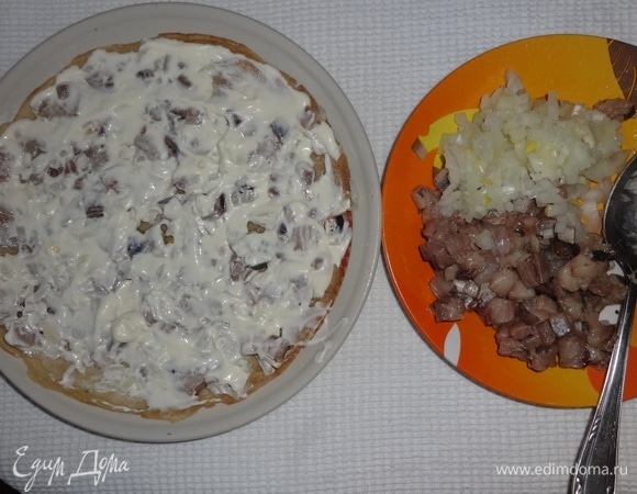 На плоское блюдо выложить блинчик, на него — половину нарезанной сельди и половину лука, смазать 3 ст. л. майонеза.