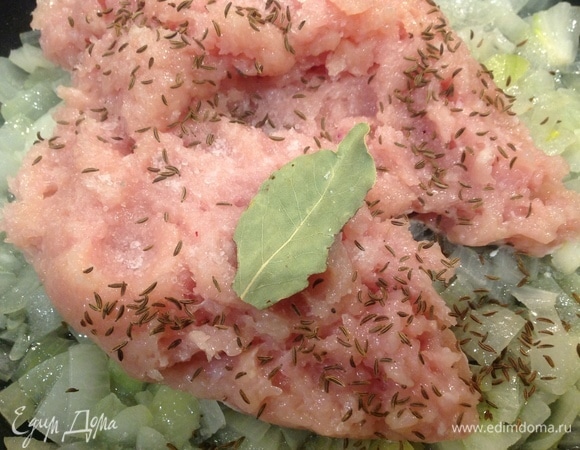 Лук нарезать и обжарить пару минут на оливковом масле. Добавить в сковородку фарш, соль, перец, тмин, лавровый лист. Обжарить 5–7 минут.