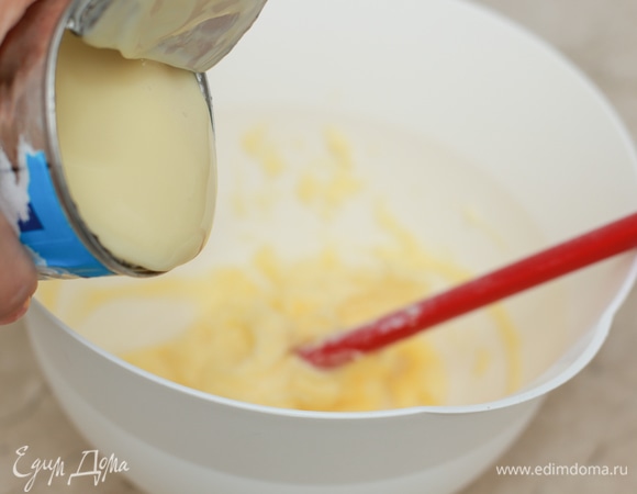 Пока выпекается корж, приготовьте крем. Крем для этих пирожных обычно делают самый простой — на сгущенке с маслом. Для этого заранее достаньте масло из холодильника, чтобы оно стало очень мягким, затем слегка взбейте его. Постепенно вливайте сгущенное молоко к маслу, каждый раз тщательно взбивая смесь миксером.