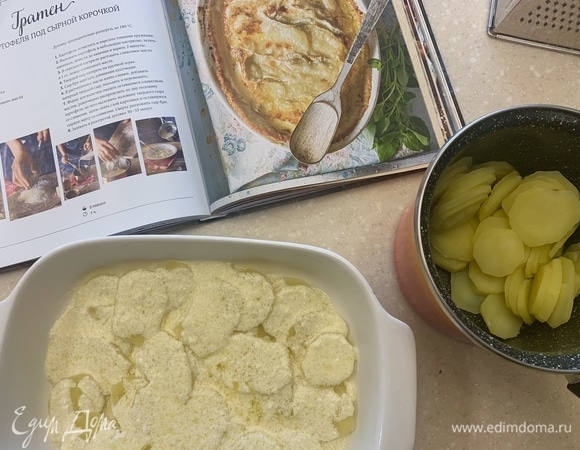 Форму для выпечки смазать оставшимся оливковым маслом, равномерно по дну распределить половину картофеля, на него выложить половину твердого сыра со сливками, затем — опять слой картошки и оставшуюся массу со сливками.