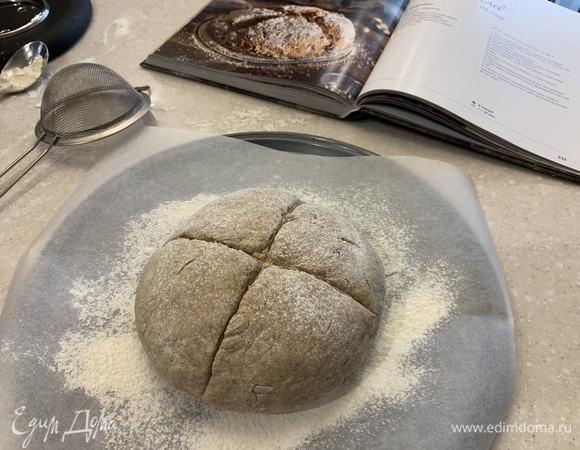 Посыпать пшеничной мукой форму для выпечки или противень и выложить тесто, сформировав круглый хлеб. Сделать на тесте глубокий надрез крест-накрест, посыпать мукой и выпекать хлеб в разогретой духовке 40–45 минут. Приятного всем аппетита!