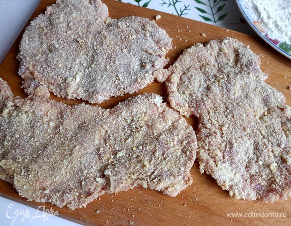 Положить шницели в панировке на деревянную разделочную доску.