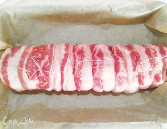 С помощью пергамента сворачиваем рулет. Перевязываем в нескольких местах кулинарной нитью.