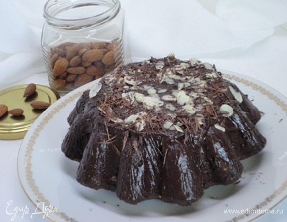 Выпекать 45–50 минут при 180°C. Для глазури смешать все ингредиенты и растопить на водяной бане. Полить глазурью остывший кекс. Украсить лепестками миндаля, шоколадом и т. п.