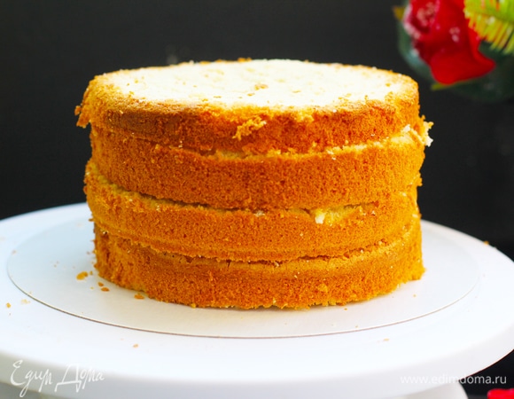 Бисквит. Яйца взбить миксером в пышную пену, добавить сахар и взбивать еще 5 минут. Муку просеять с разрыхлителем и аккуратно ввести в яичную смесь, перемешать на низких оборотах миксера или вручную. Добавить масло и кипяток и снова все перемешать. Формы (я делала в 2 формах по 16 см) застелить снизу бумагой, борта не смазывать! Разлить тесто по формам равномерно. Выпекать при 180°C 30–40 минут. Вынуть формы, перевернуть на решетку и остудить бисквиты полностью. Вынуть бисквиты из форм, перемотать пищевой пленкой и положить в холодильник на ночь. Так тесто будет меньше крошиться при нарезке, и влага внутри перераспределится равномерно по всему коржу. Перед сборкой коржи достать, отрезать крышечку, если бисквиты вышли с горочкой, разрезать пополам.