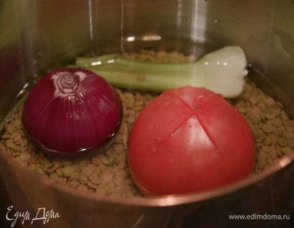В глубокую кастрюлю поместить помидор, надрезанный крестом, сельдерей, красную луковицу, один зубчик чеснока, всыпать чечевицу, залить водой и варить до готовности без добавления соли.