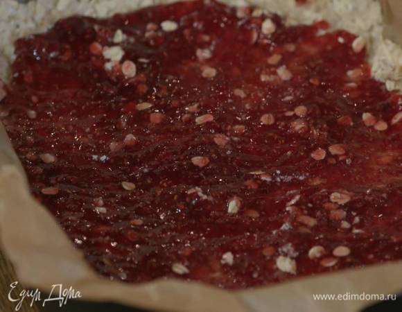 Небольшой противень с высокими бортиками выстелить бумагой для выпечки, выложить овсяную массу и плотно утрамбовать, сверху равномерно распределить малиновый джем.