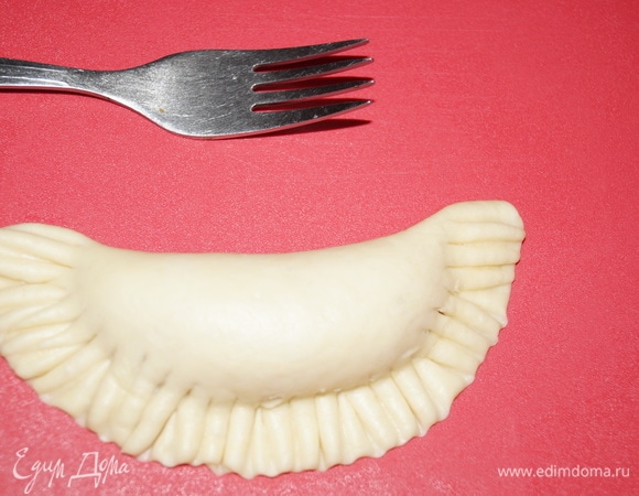 Края чебурека сначала соединила руками, а затем закрепила зубчиками вилки. Место, где находится начинка, осторожно придавила ладонью, чтобы фарш равномерно распределился и хорошо прожарился.