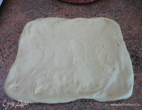 Подошедшее тесто выкладываем на рабочий стол, не подсыпая муки, так как оно совершенно не липнет, и аккуратно растягиваем в прямоугольный пласт.
