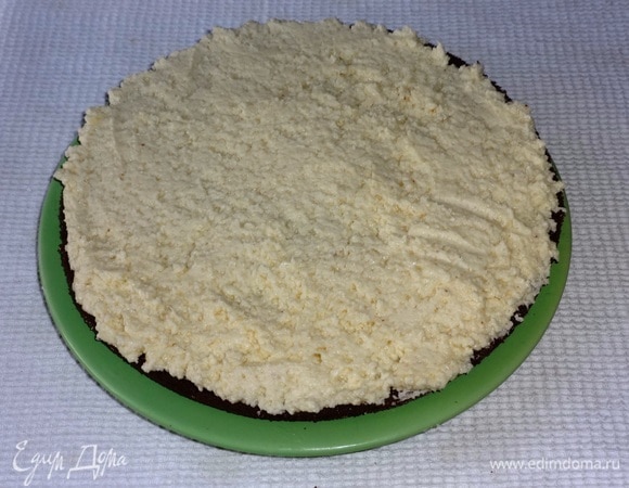 Выложить пласт на блюдо и смазать 1/3 частью крема, разровнять. Выложить следующий пласт, смазать 1/3 крема. Выложить последний пласт. Смазать кремом кольцо верхнего пласта, оставляя круг посередине, и бока торта. Желательно брать блюдо с плоским дном, а то я взяла с углублением, и поэтому торт получился не совсем правильной формы.