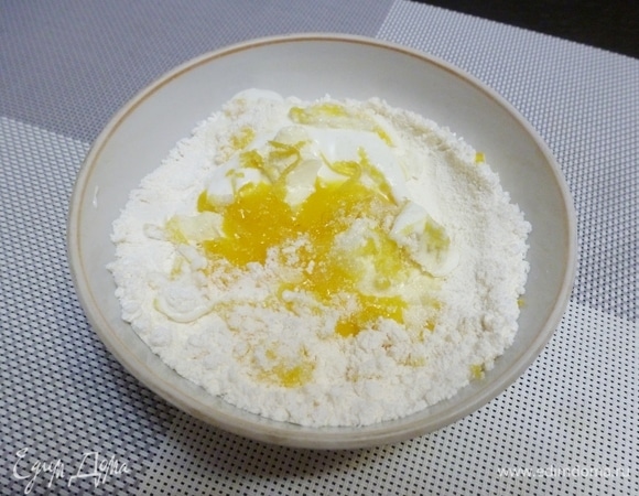 В миске смешать муку с разрыхлителем и со сливочным маслом (мягким). Просто порубить ножом или вилкой, чтобы получилась крошка. Добавить остальные ингредиенты: сметану, желтки, ванильный сахар, цедру лимона и 1 чайную ложку сахара. Остальной сахар пойдет на посыпку печенья.