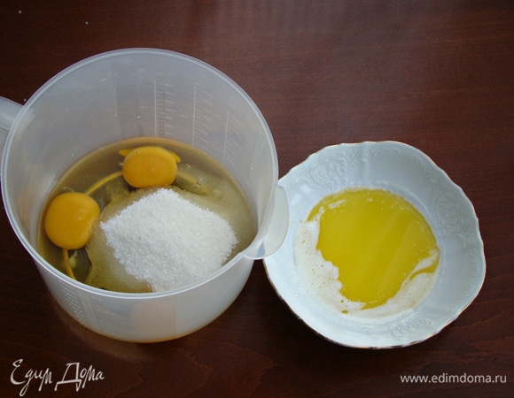 Сливочное масло растопить и остудить до комнатной температуры. Яйца взбить с сахаром в пышную светлую массу. Затем к этой массе влить остывшее сливочное масло и все перемешать до однородности.