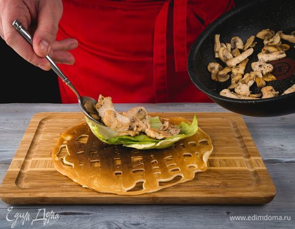 На каждый блин положите по листу салата. Сверху выложите начинку из курицы и шампиньонов.