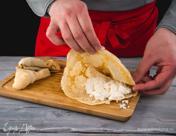 Выложите готовый творог в середину каждого блина, сверните в виде конверта.