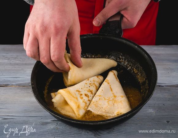 Блинчики сложите в 4 раза и выложите в сковороду. Пропитайте блины соком по несколько минут с каждой стороны.