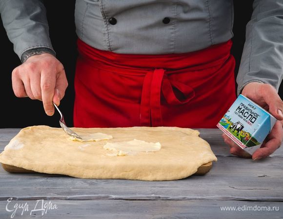 Каждую часть раскатайте в тонкий пласт. Смажьте пласты теста сливочным маслом ПравильноеМасло АО АИСФеР.