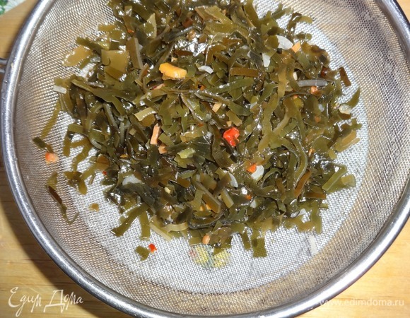Салат из маринованной морской капусты откинуть на сито и дать стечь маринаду.